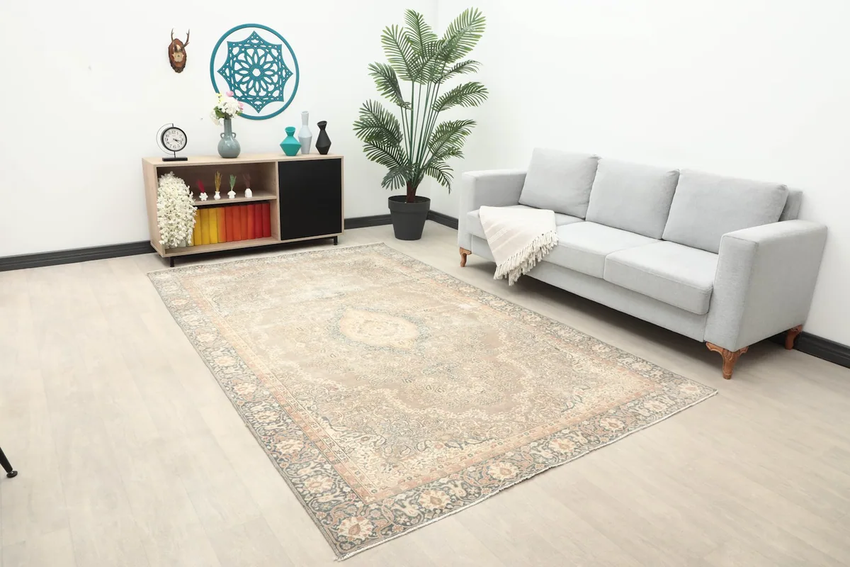 Beige medallion rug in a room setting, showing its scale next to a sofa and cabinet