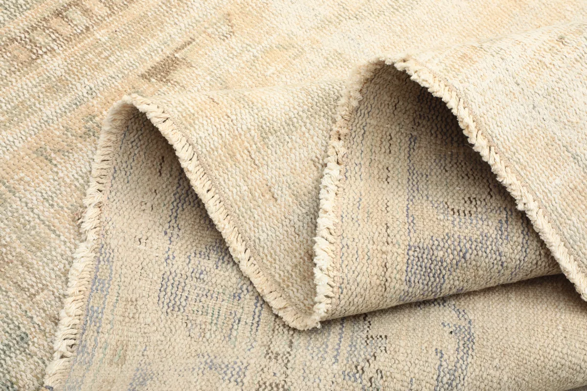Close-up of the rug folded, revealing the tight weave of the wool pile and cotton foundation.