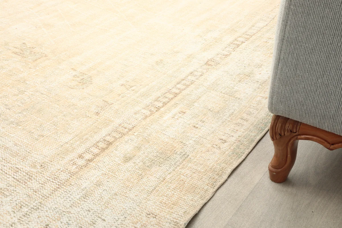 Close-up of the rug's border next to furniture, showing the subtle color variations and low pile.