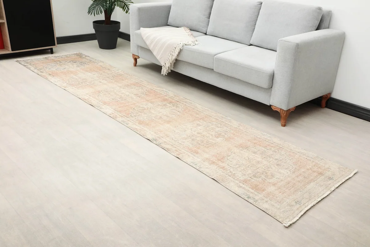 Overhead view of the vintage runner rug in a room, highlighting its faded colors and geometric pattern.