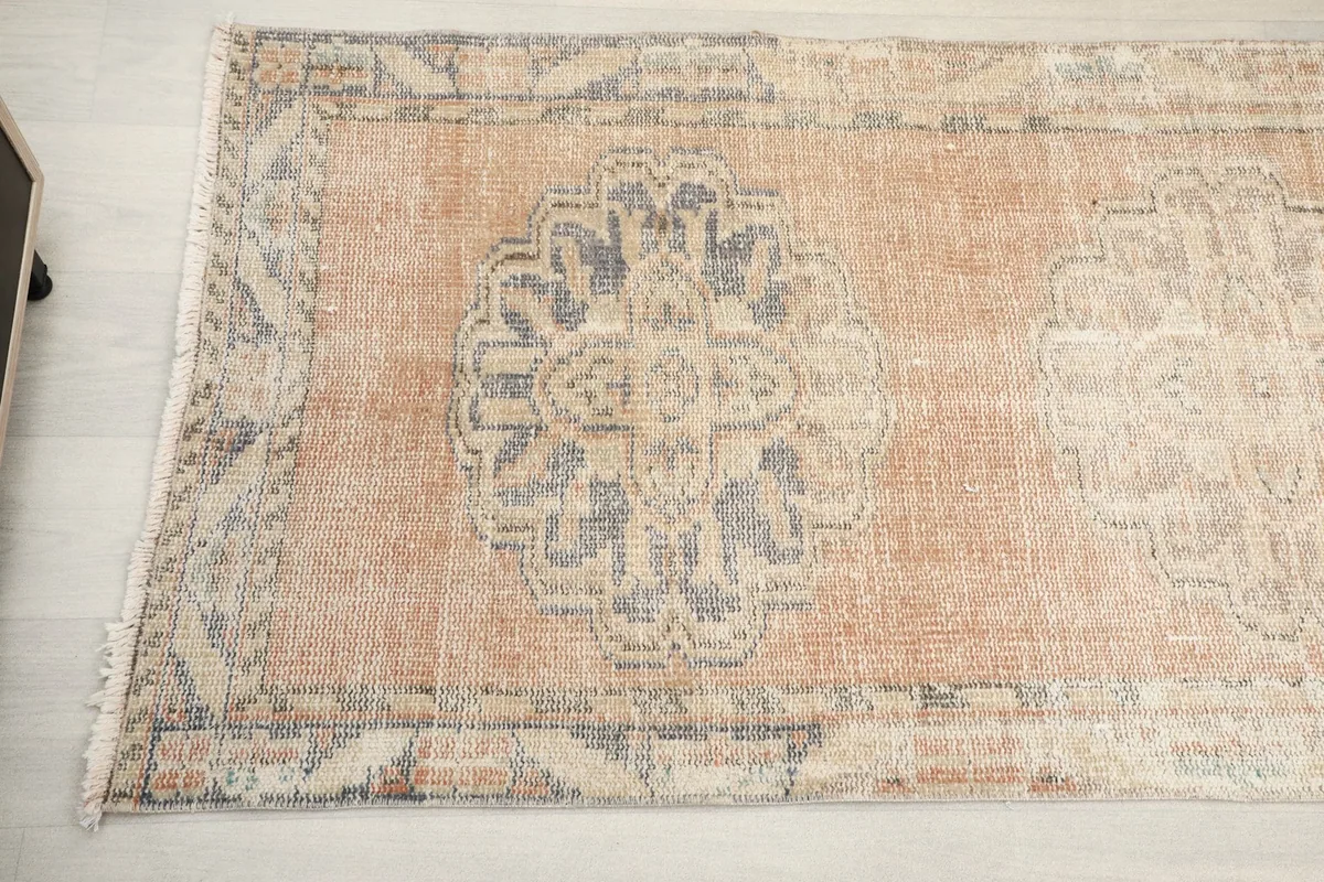 Detailed view of a geometric medallion with hints of blue in the center on the vintage runner rug.