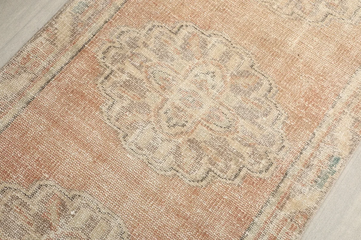 Angled close-up showing the texture and faded colors of a gray medallion on the rust field.