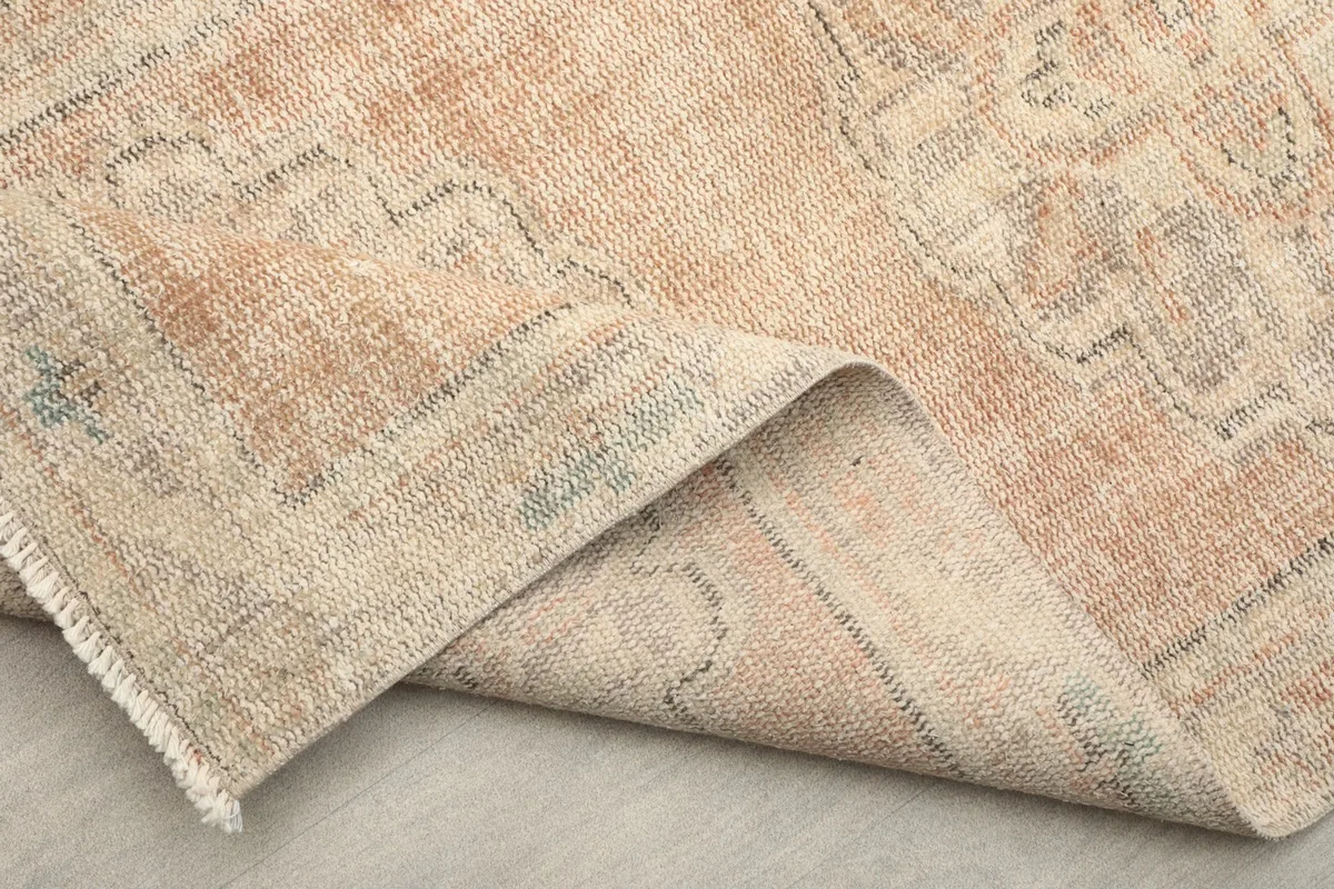 Close-up of the border pattern and the faded rust main field of the vintage runner.