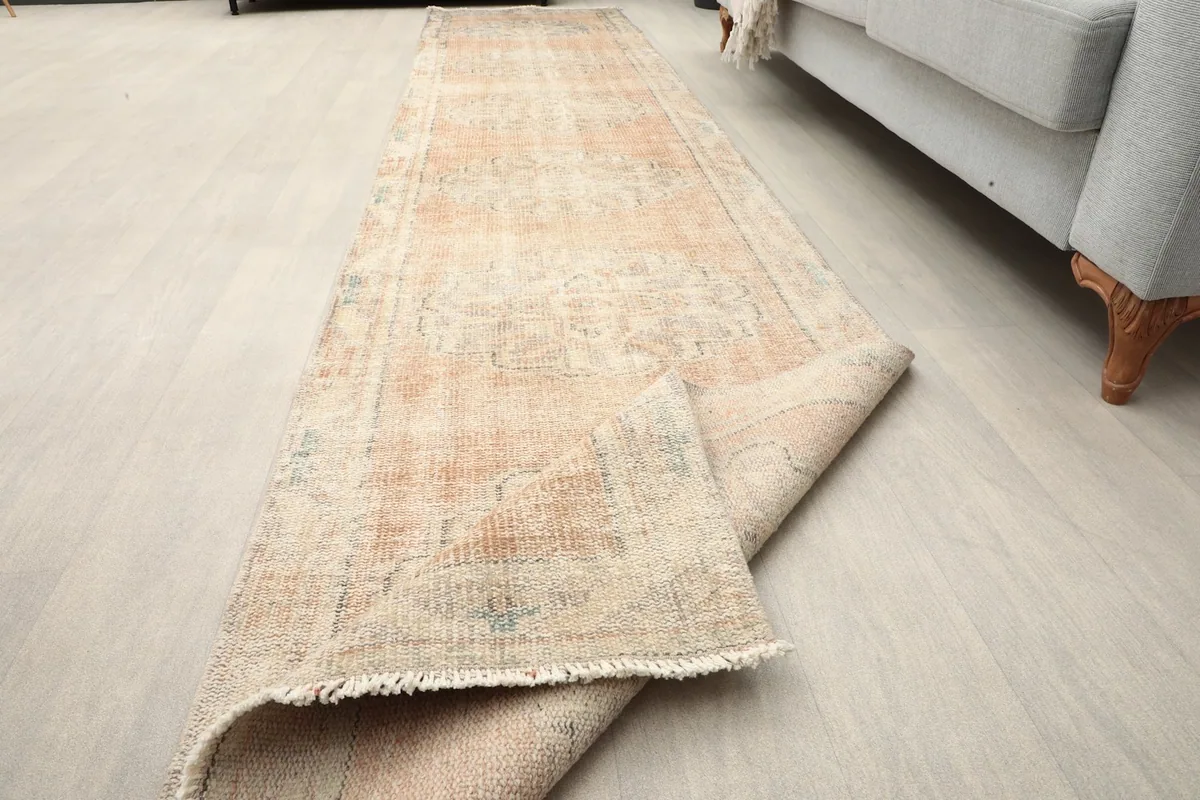 Corner of the runner rug folded back, revealing the fringe and construction.