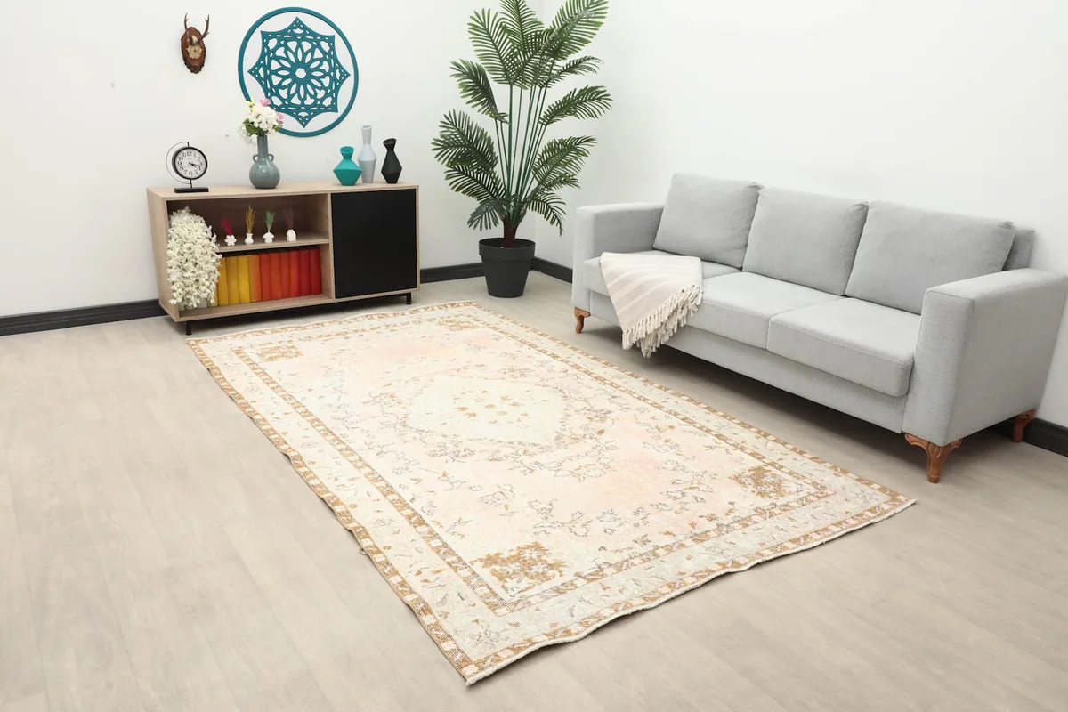 Angle view of the Rose Tan Medallion rug in a living room with a sofa and cabinet
