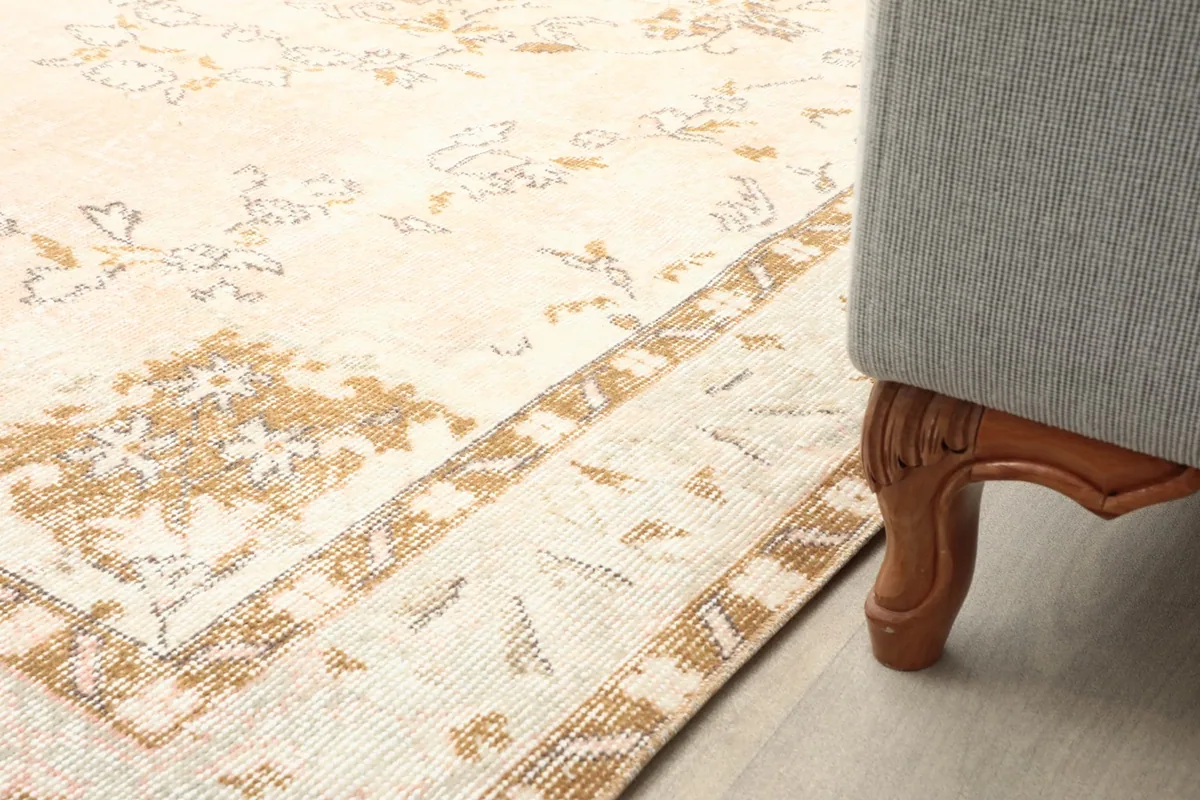 Close-up of the rug's border next to a sofa leg, showing the subtle wear and design