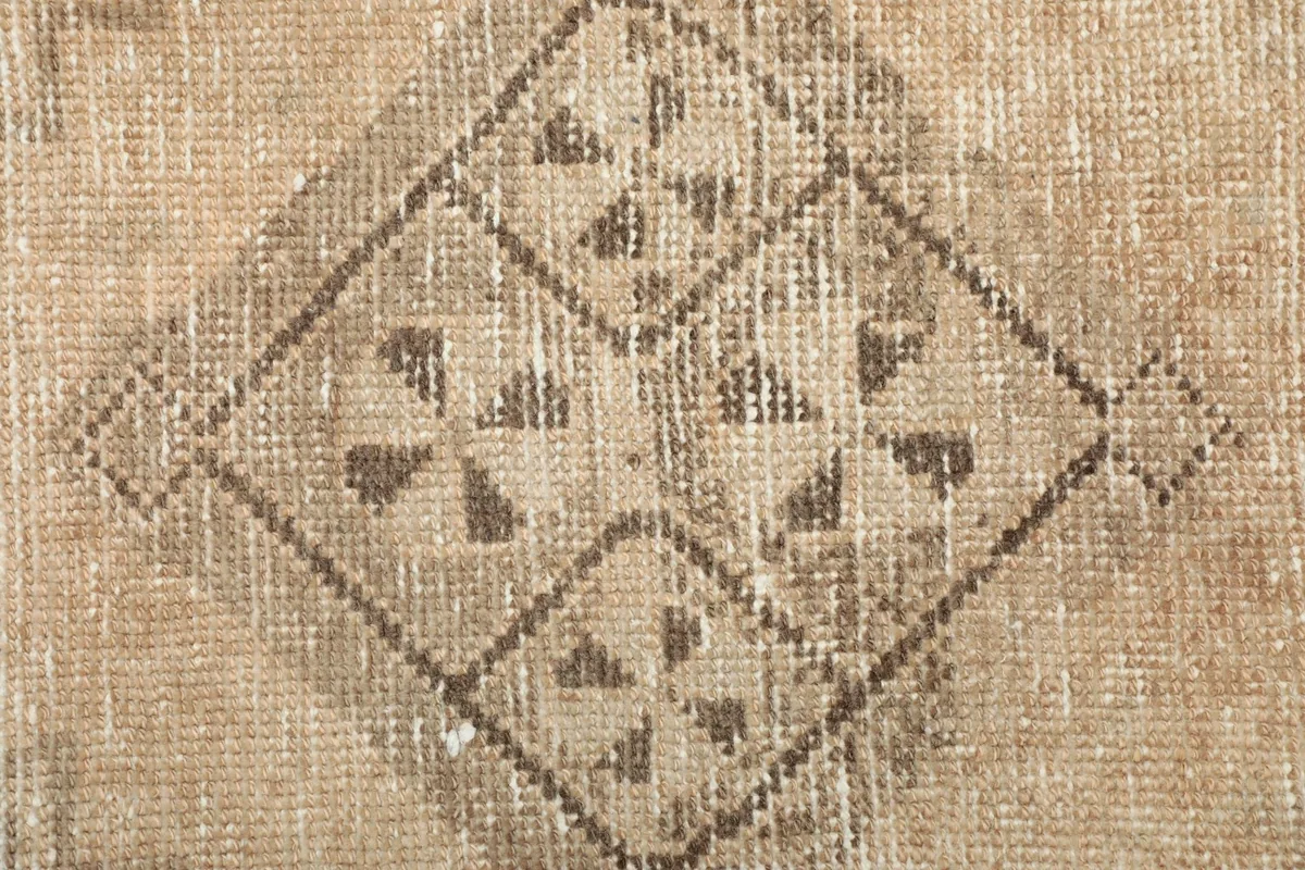 Extreme close-up of a specific geometric pattern, revealing the worn texture and knotting.