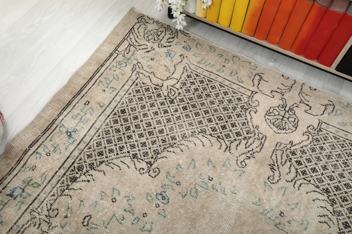 Corner view of the vintage rug, showing the blend of tan and charcoal colors