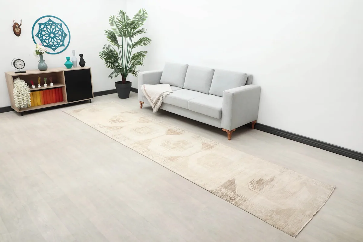 Wide shot of the room showing the vintage runner rug, a sofa, and decorative elements.