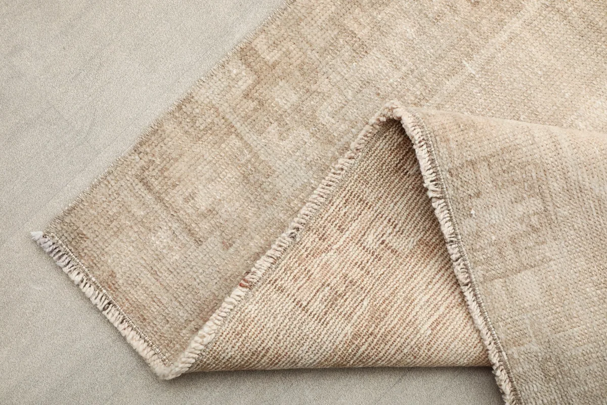 Close-up of the rug's edge and fringe, with a corner folded back to show the construction.
