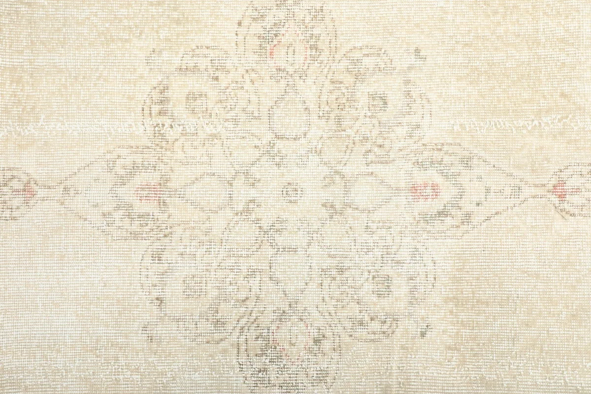 Close-up of the central medallion design in muted rose and gray on the ivory field