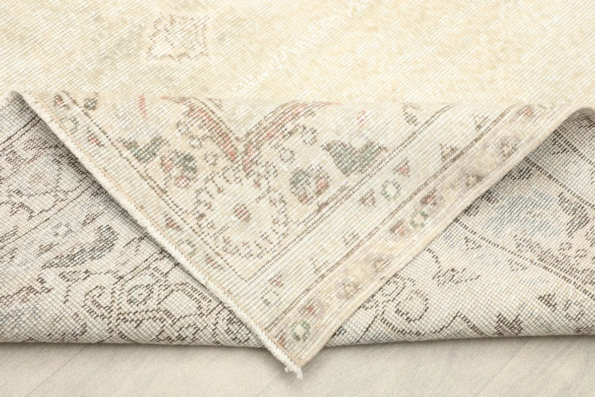Folded corner of the rug revealing the cotton foundation and reverse side of the knots