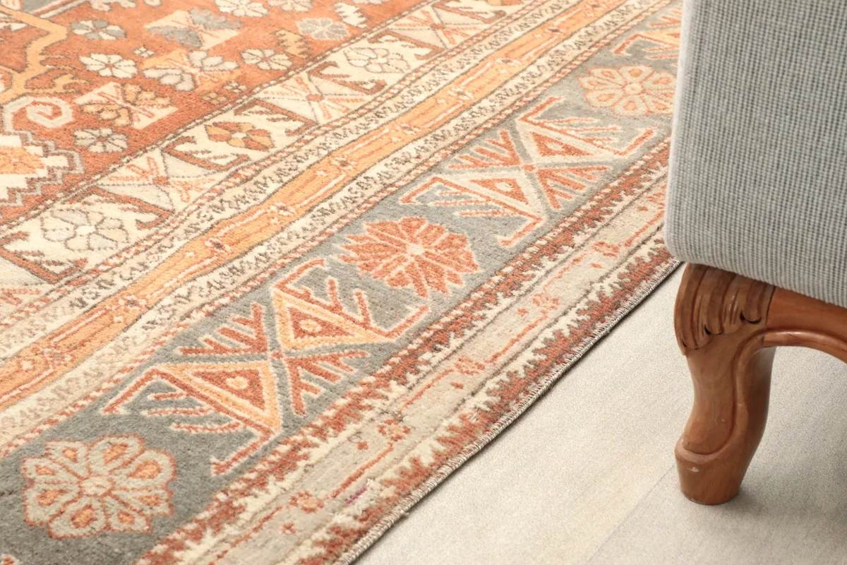 Side view of the rug next to a sofa leg, highlighting the border design