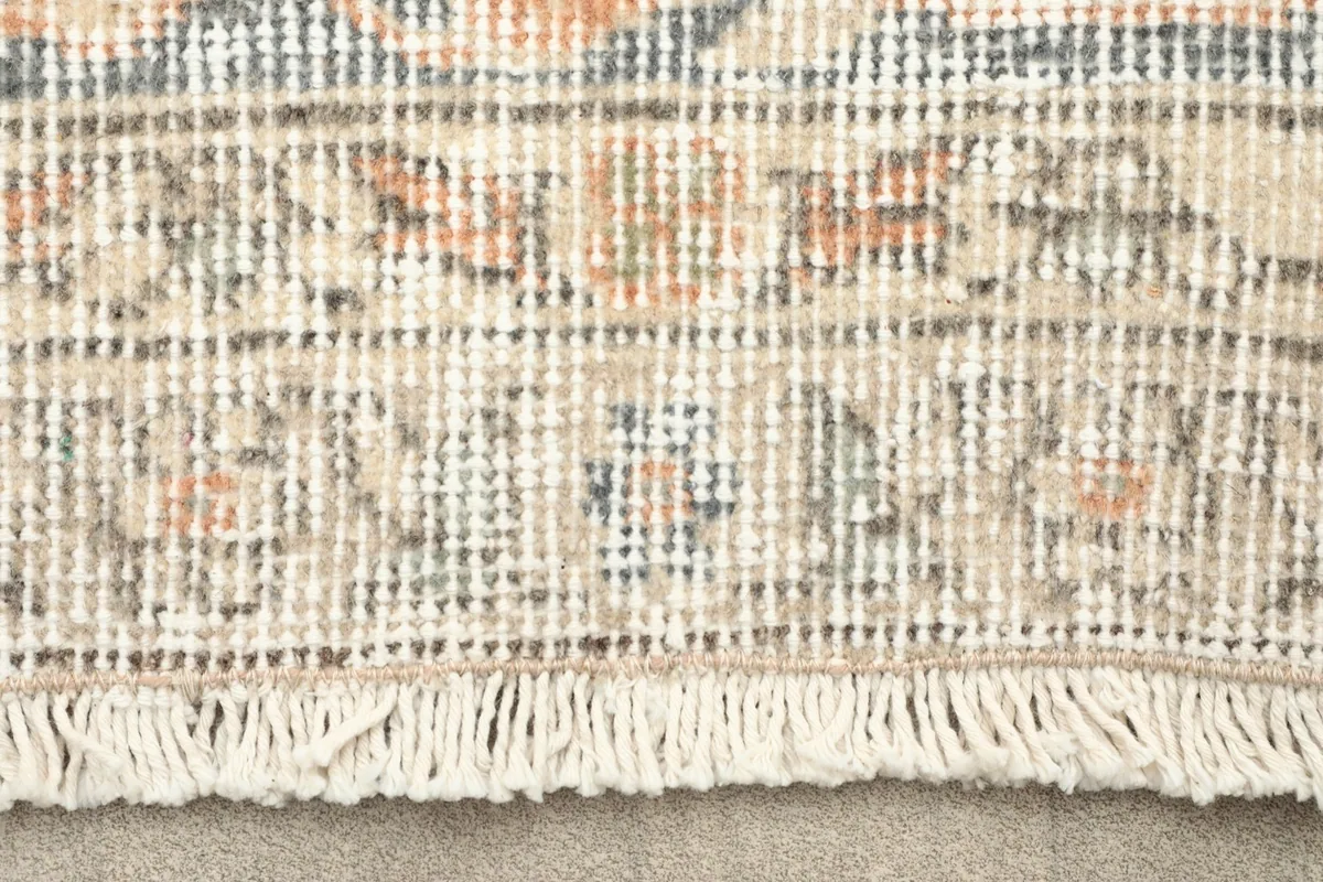 Close-up detail of the rug's short, natural fringes and hand-knotted pile