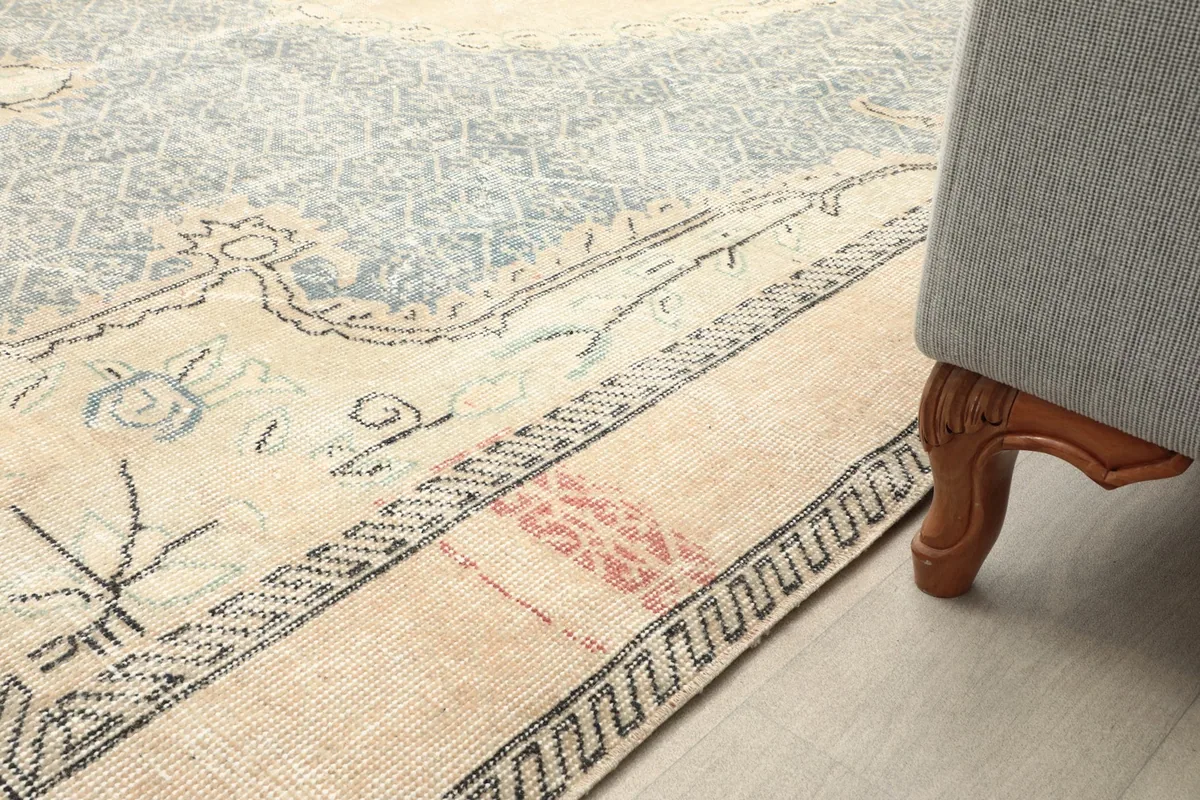 Close-up of the rug's border design next to a furniture leg, showing color variation