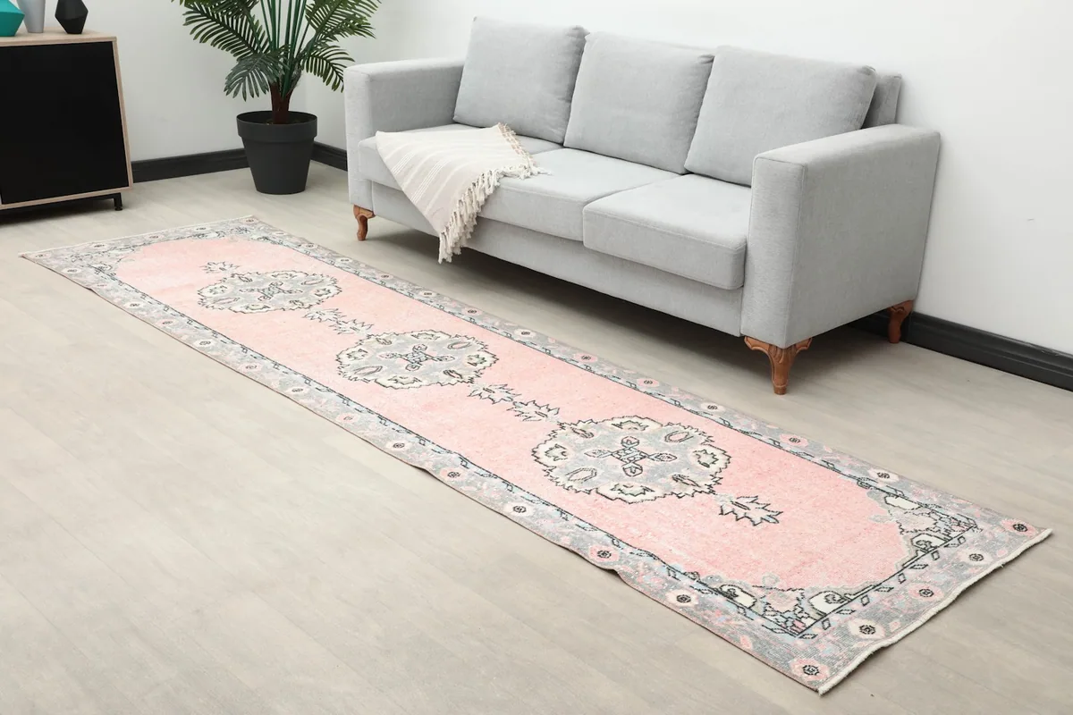 Angle view of the runner rug in a room, showing its length next to a sofa and plant.