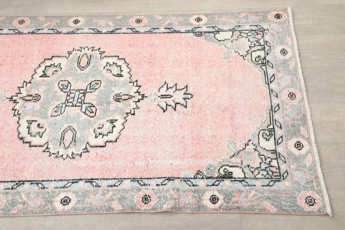 Close-up detail of the rose field, gray border, and geometric medallion at one end of the runner.