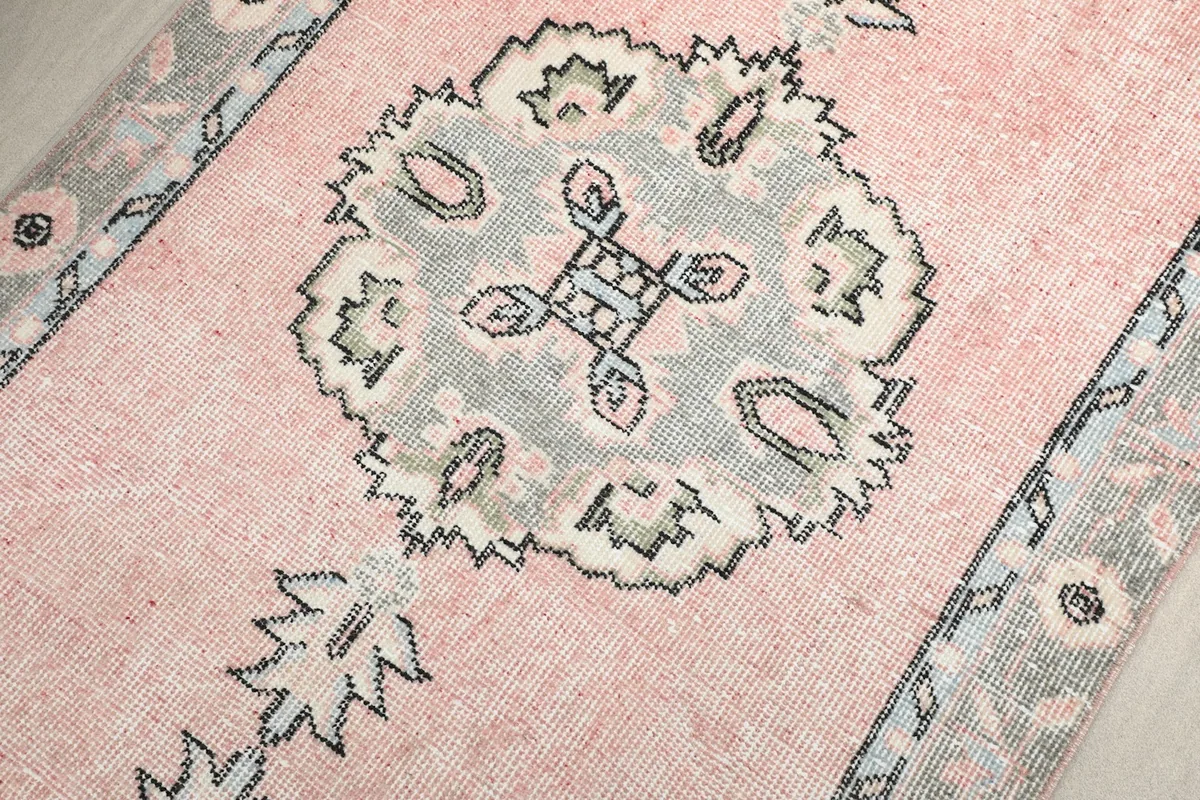 Close-up of a central geometric medallion with gray, ivory, and blue accents on the rose field.