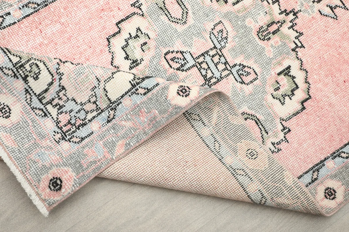 Close-up of the folded rug, showing the cotton foundation and the reverse side of the hand-knotted construction.