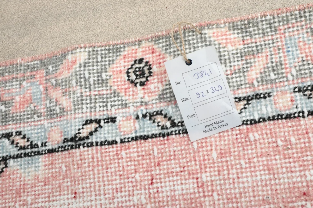 Close-up of a tag attached to the rug's edge, showing the dimensions and 'Hand Made in Turkey' label.