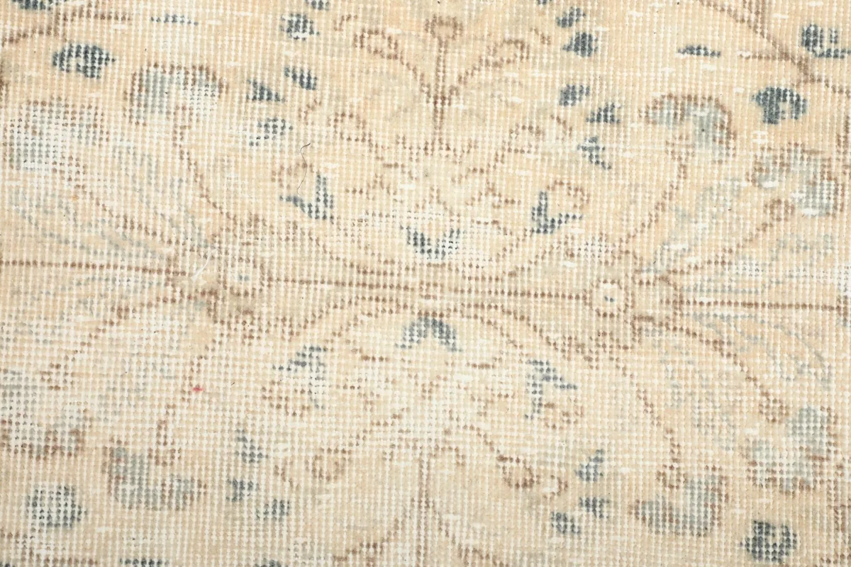 Macro detail of the hand-knotted wool pile and the worn, distressed texture of the rug.