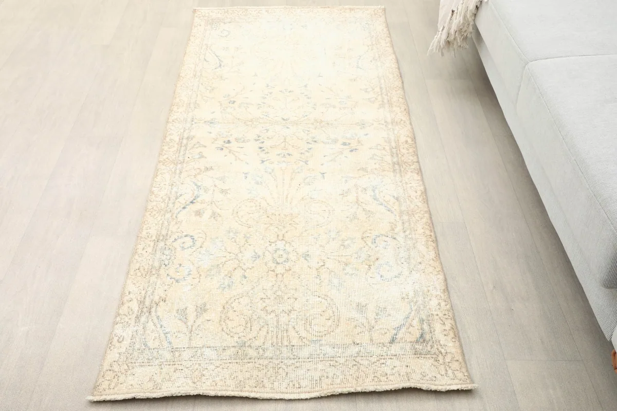 Overhead view of the ivory beige floral runner placed on a light wood floor next to a sofa.