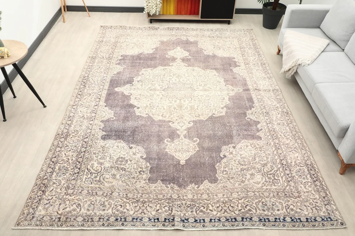 Vintage purple and ivory rug displayed in a living room setting with a light gray sofa and modern decor.