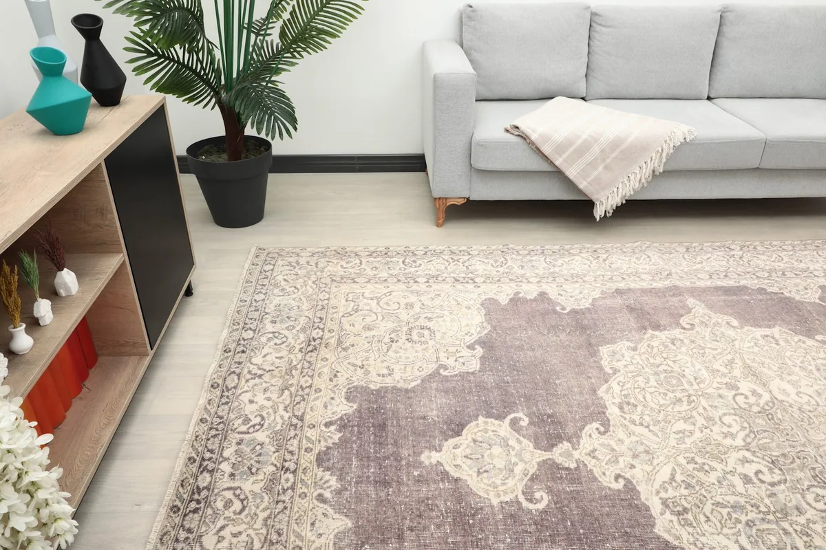 View of the rug in a room setting, focusing on the purple field and ivory medallion from a lower angle.