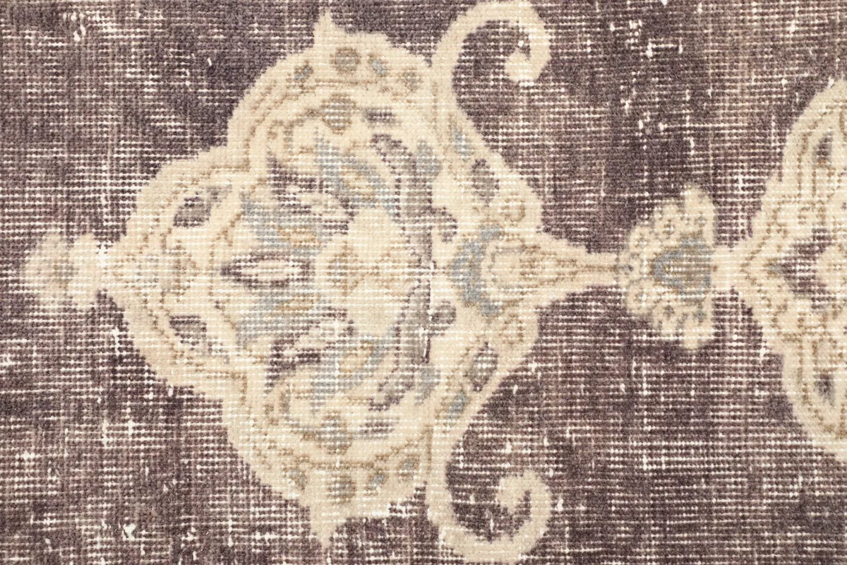 Detailed view of the rug's surface, showing the faded purple pile and ivory patterns with subtle blue tones.