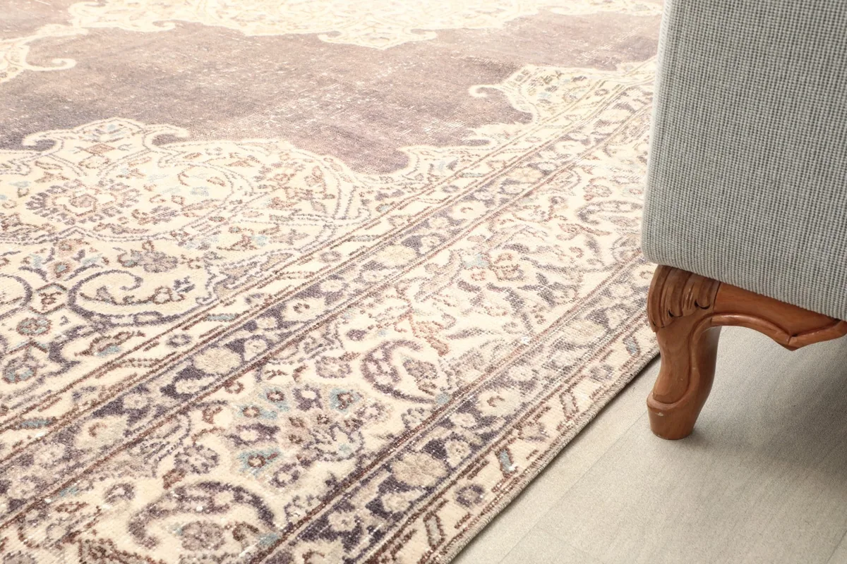 Close-up of the rug's low pile texture and patterns, with the leg of a sofa visible in the foreground.