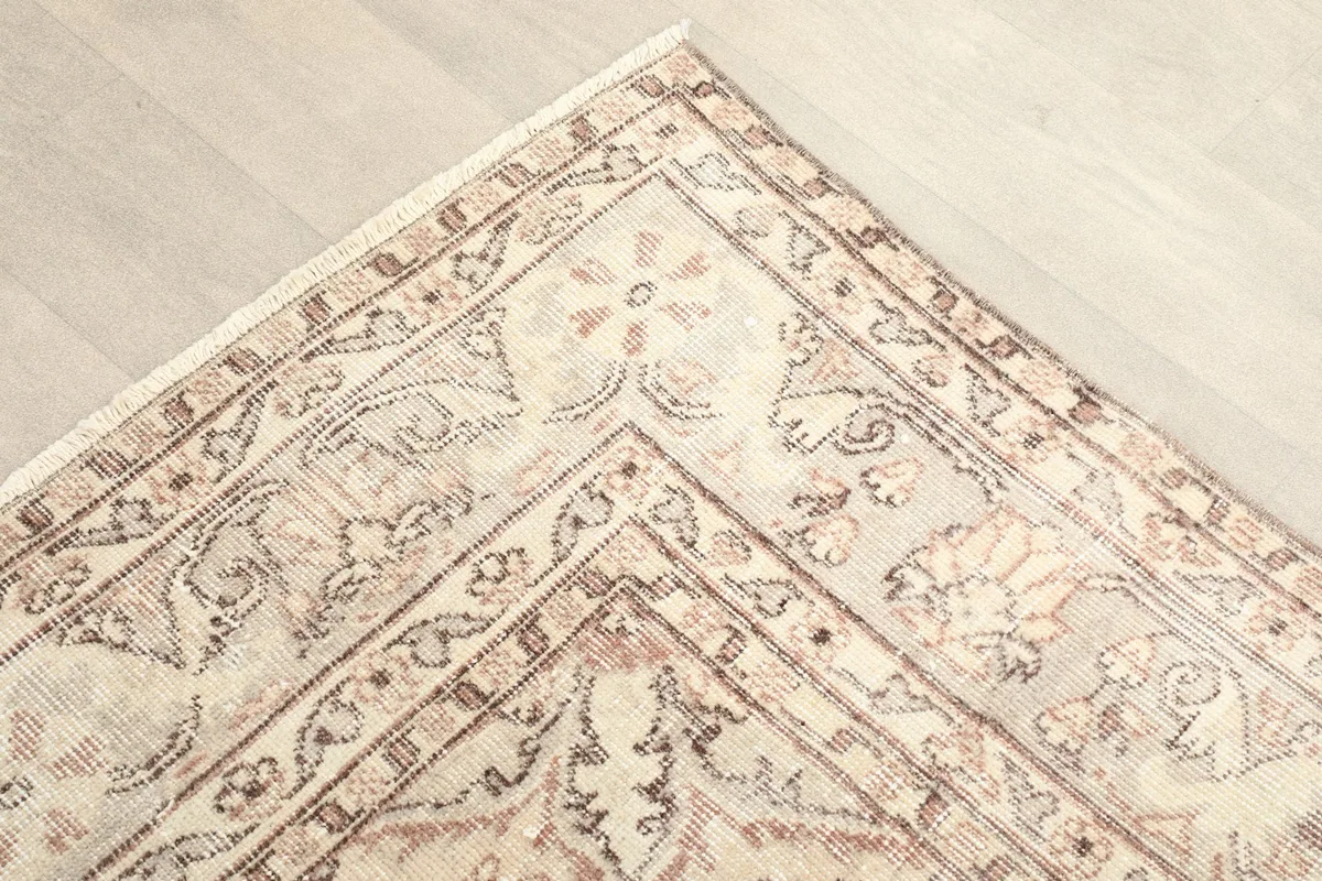 Corner detail showing the intricate border patterns in brown and rust on an ivory background