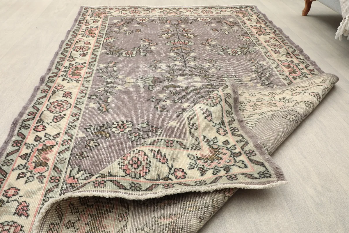 Angled view of the rug with one corner folded back, displaying both the front and back of the rug.