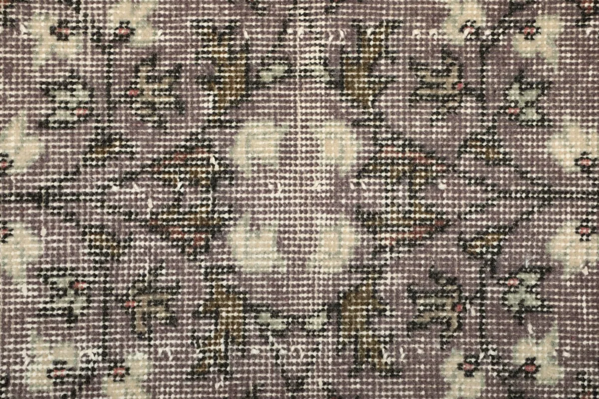 Macro view of the hand-knotted wool pile, revealing the texture and distressed nature of the rug.