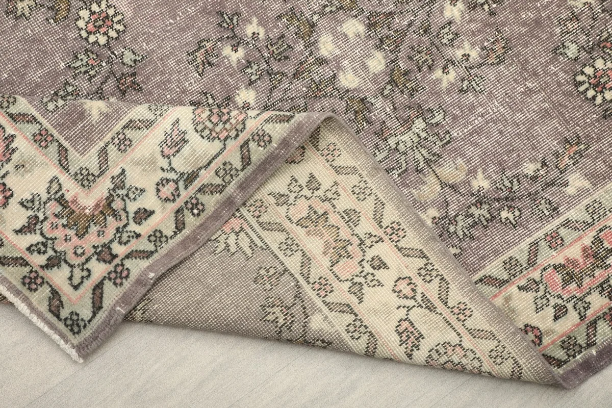 Backside of the rug partially folded, revealing the cotton foundation and hand-knotted construction.
