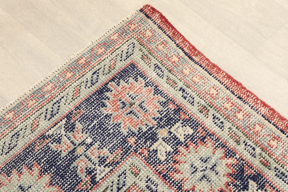 Corner view of the rug, showing the navy border and subtle geometric details