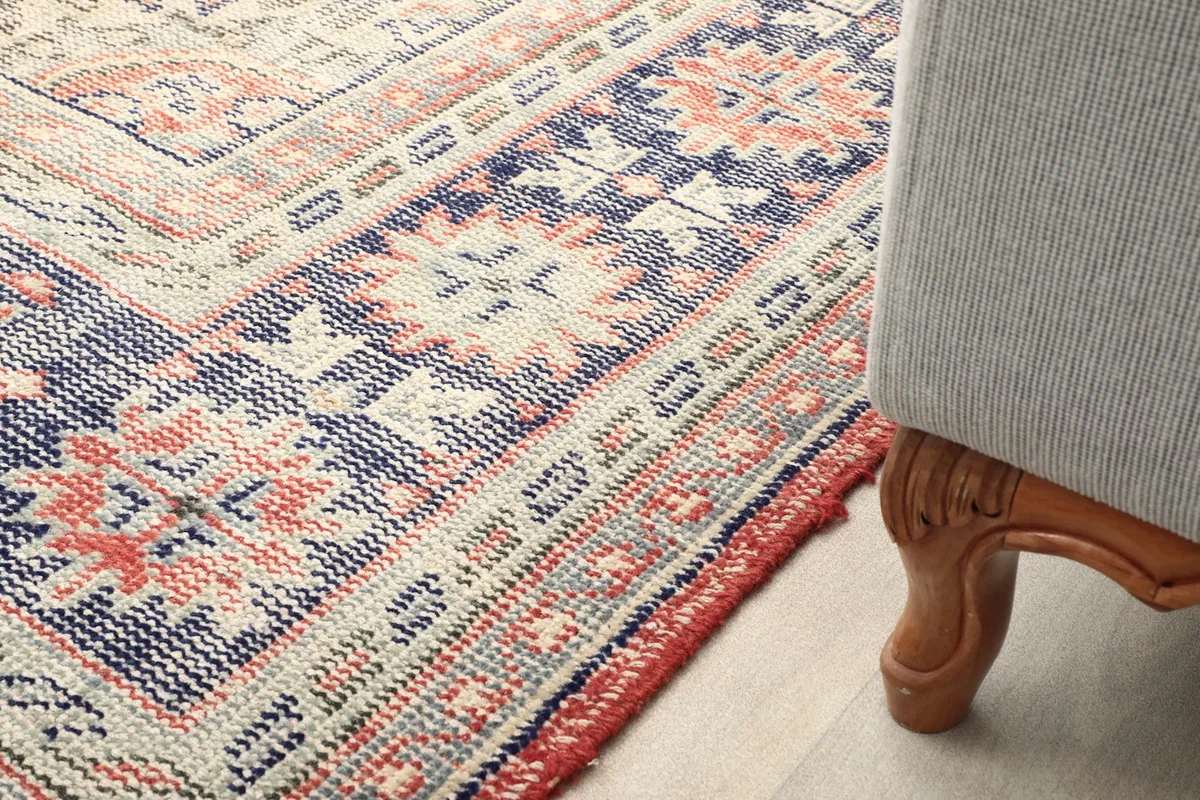 Rug corner next to a sofa leg, illustrating the scale and how it complements furniture