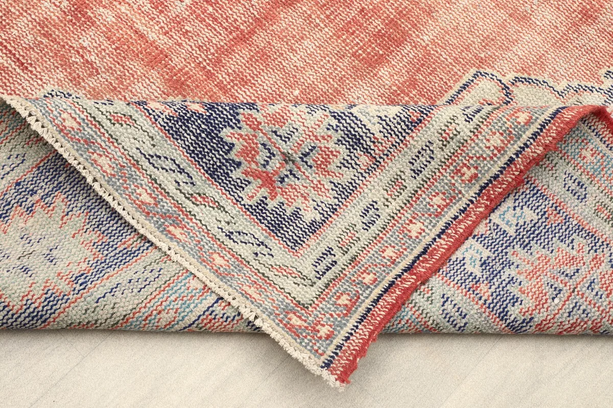Folded corner revealing the back of the hand-knotted rug, showing the cotton foundation