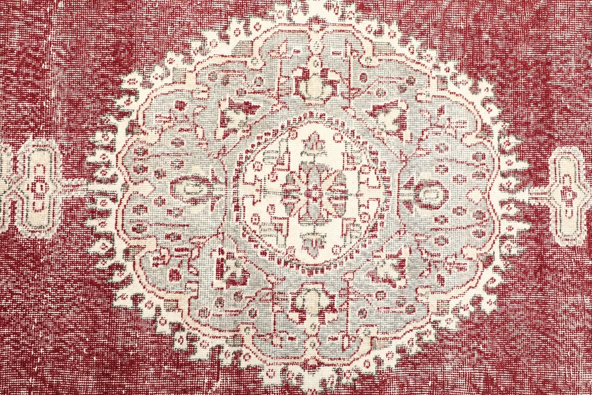Detailed view of the central medallion pattern in ivory, gray, and red with intricate motifs