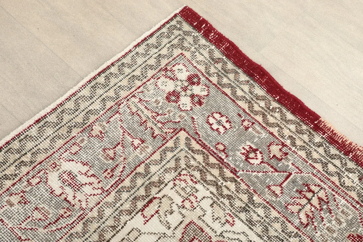 Corner detail of the rug's ivory and gray border with floral and geometric designs