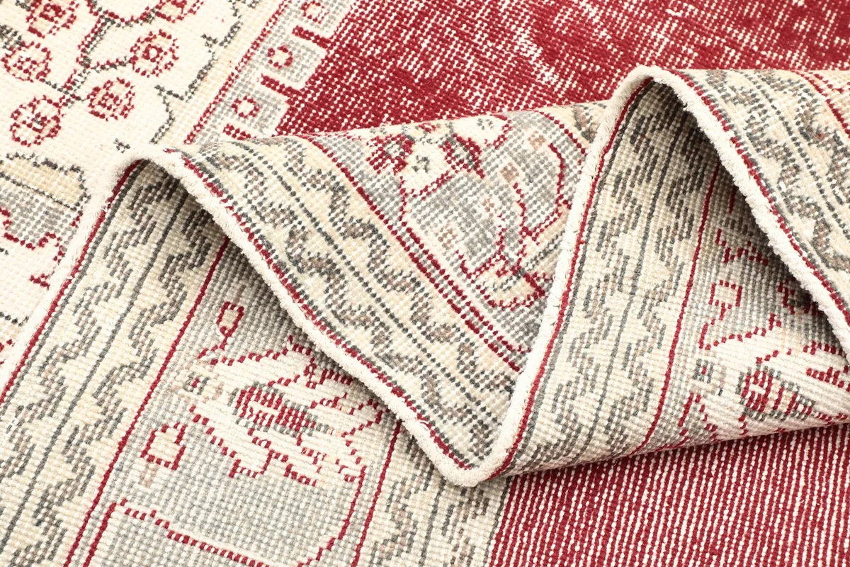 Detailed view of the rug's border and a section of the red field, showing the low pile texture