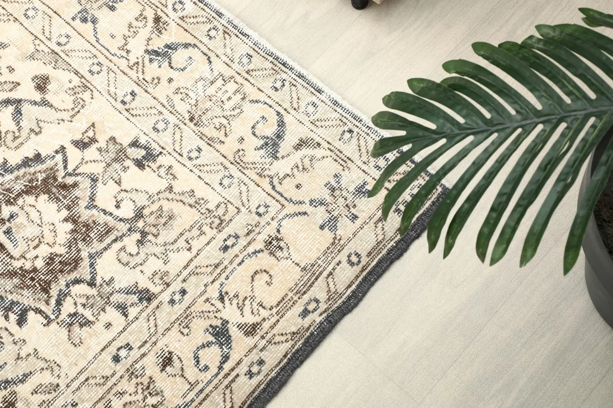 Side view of the rug's edge and border patterns next to a green plant