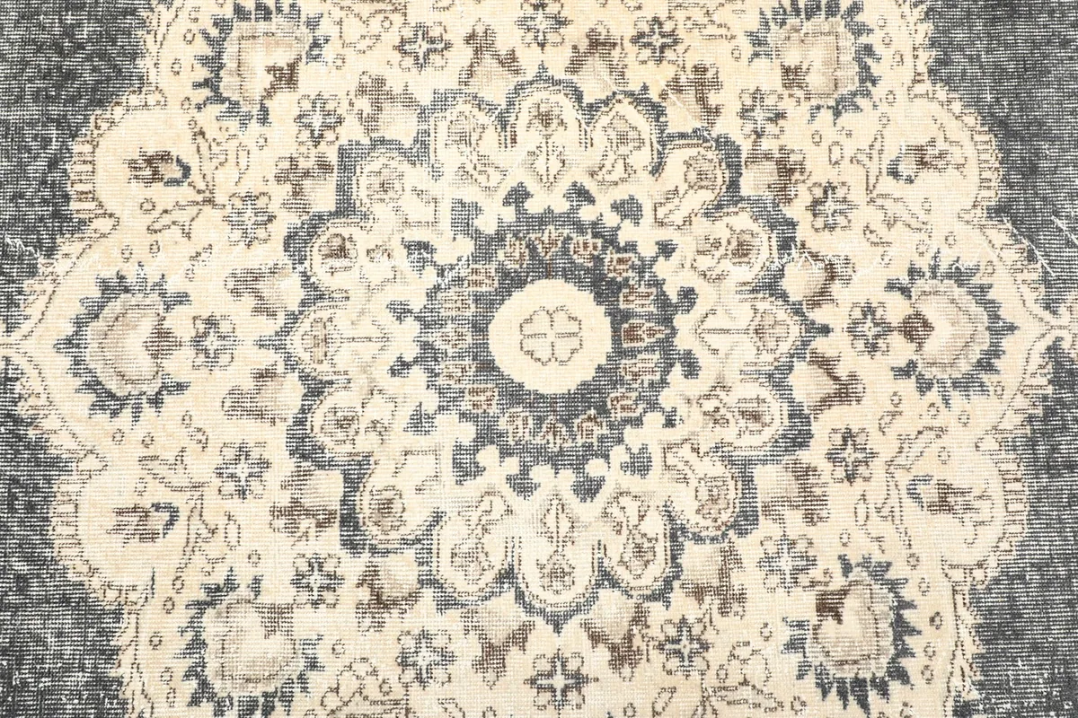 Close-up of the central medallion design with floral patterns in charcoal, ivory, and brown