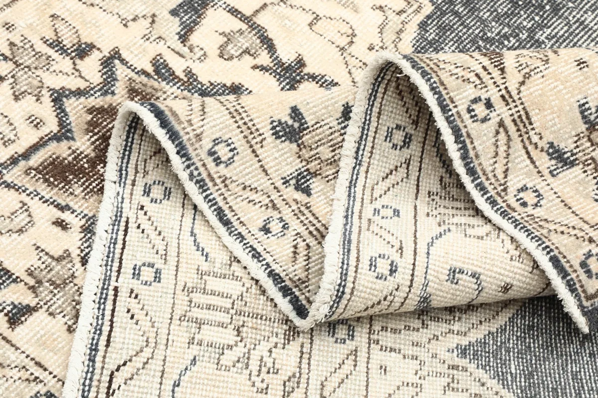Rug folded to show the texture and varied patterns along the ivory field
