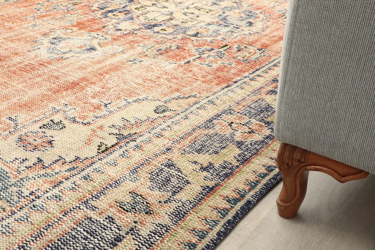 Rug placed next to a sofa leg, showing part of the border and field pattern