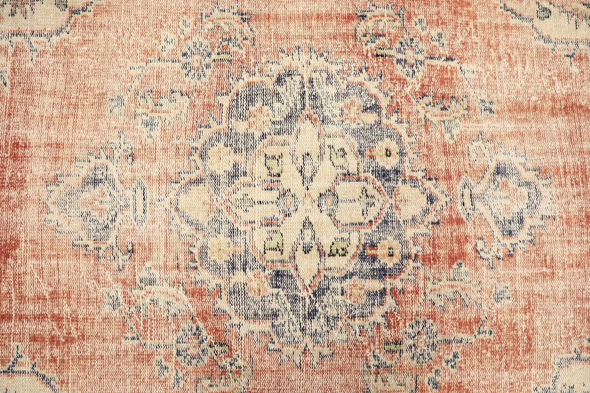 Close-up of the central medallion design with navy, beige, and green elements