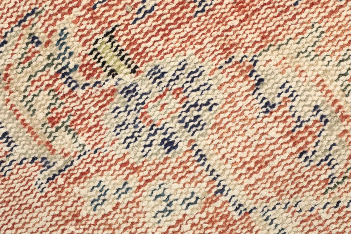 Texture close-up of the low wool pile showing rust, navy, and beige threads