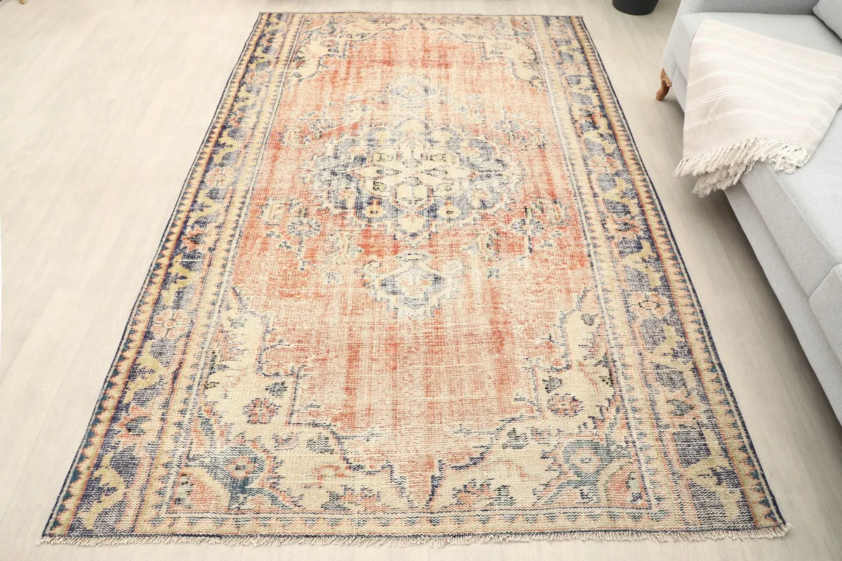 Vintage rust area rug with navy border and central medallion on a light floor