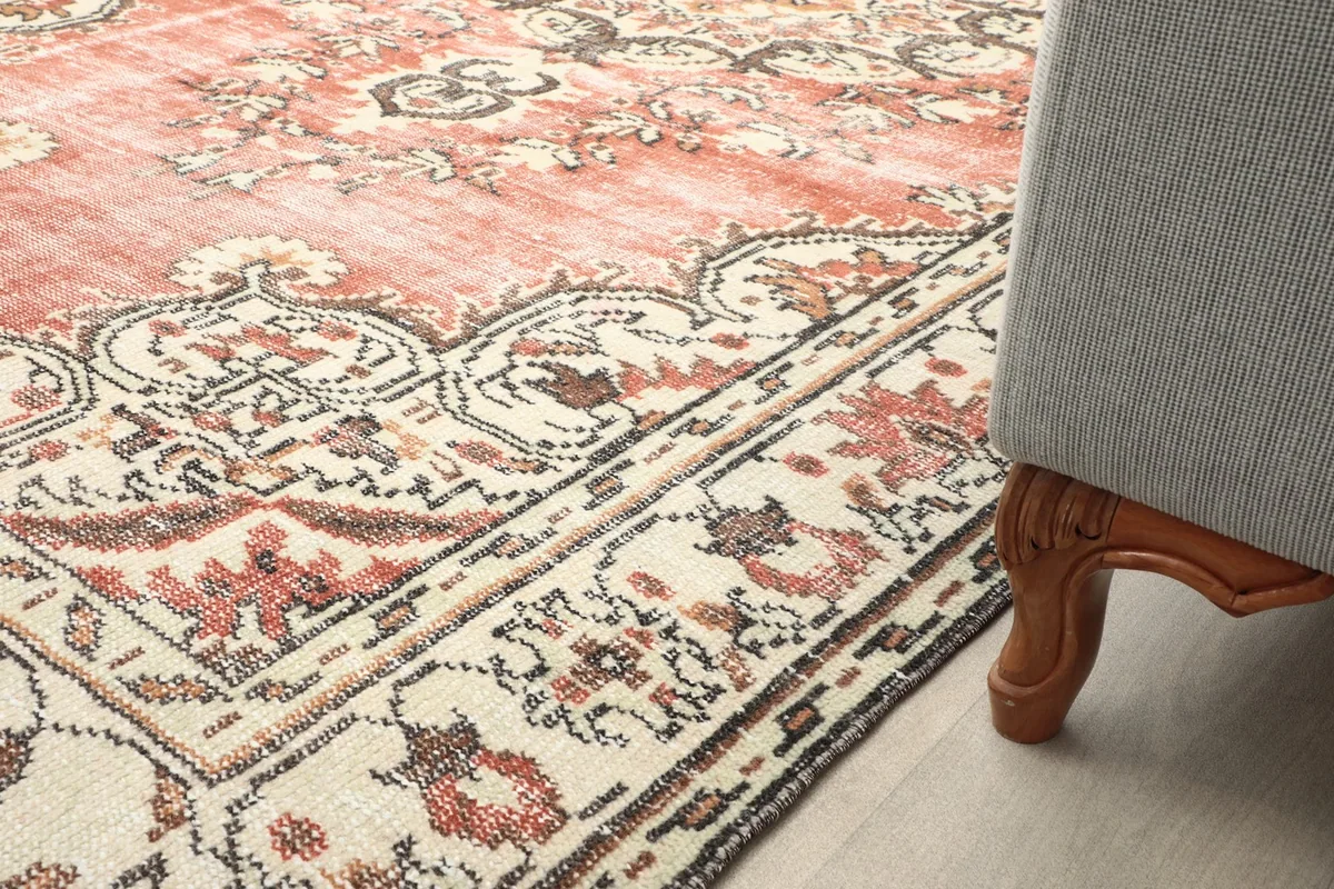 Close-up of the rug's border next to the leg of a sofa, demonstrating its scale and texture in a living space.