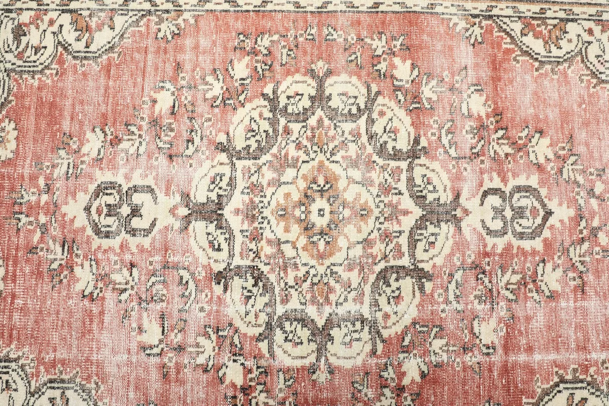 Close-up of the central medallion and surrounding floral motifs in rose, beige, and charcoal tones.
