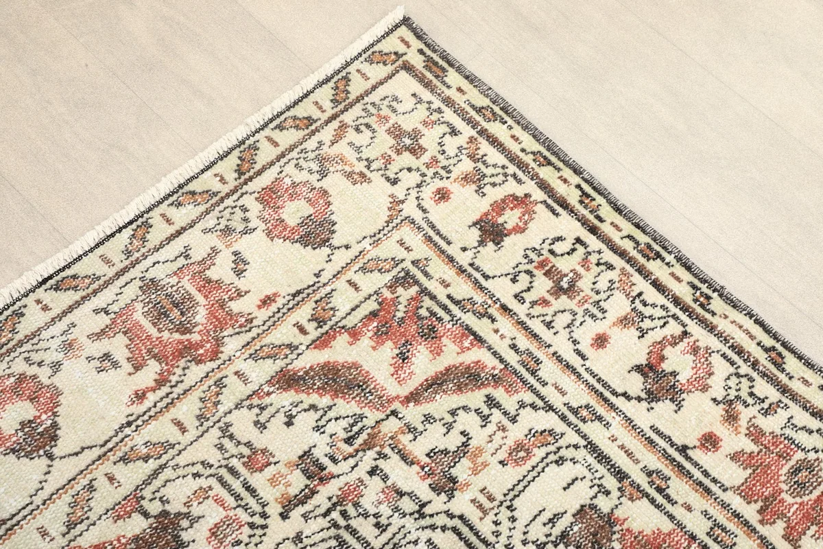 Corner detail showing the intricate patterns within the beige border and the main field of the rug.